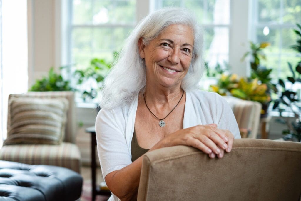 A woman sitting in front of a chair smiling.